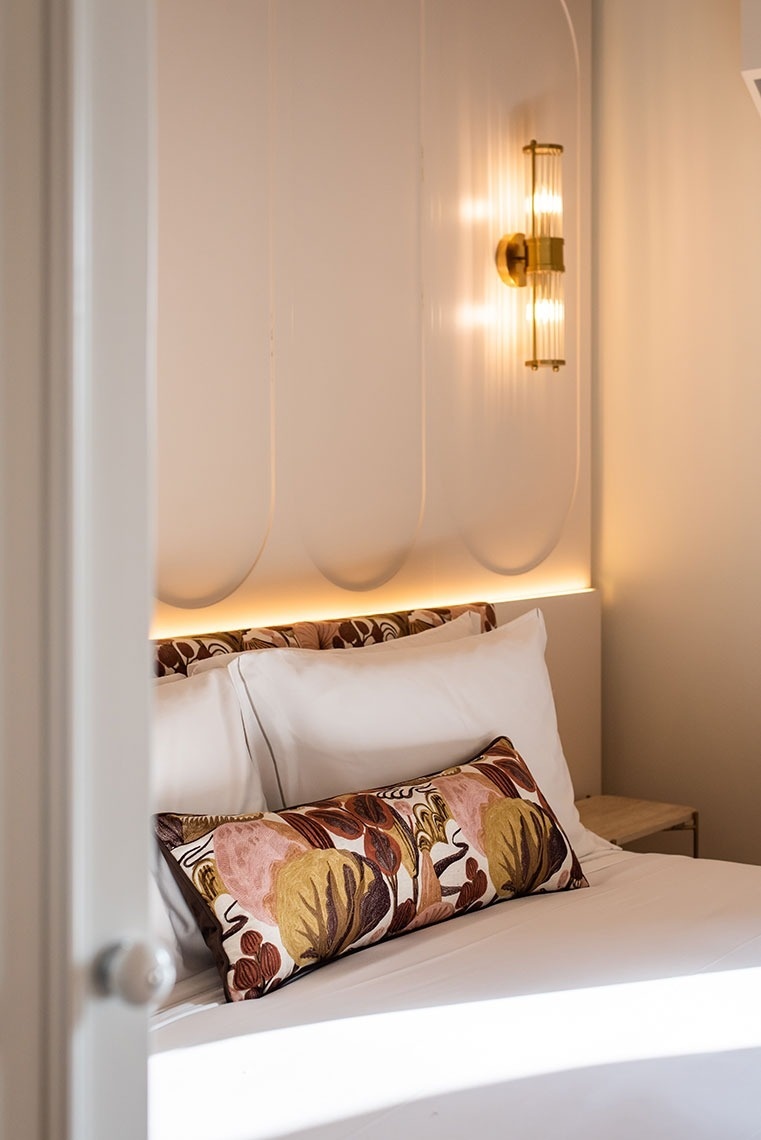 Quarto de hotel com cama confortável, cabeceira iluminada, luminária moderna e almofada decorativa. Estilo e aconchego.