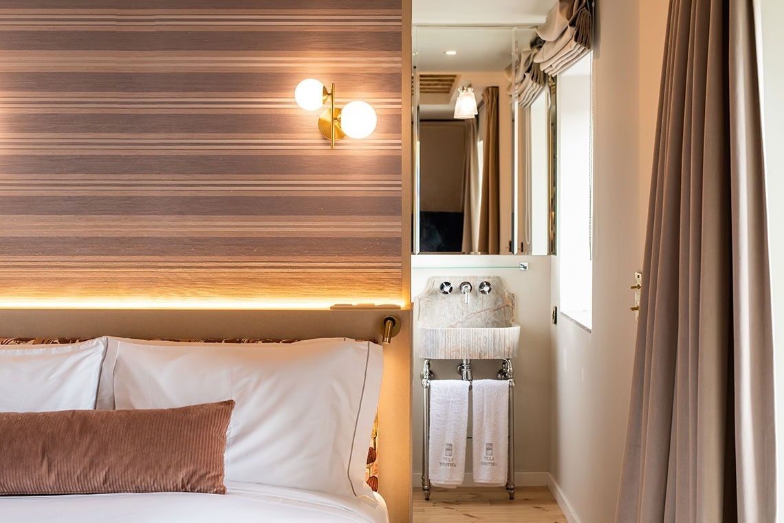 Quarto de hotel boutique com design moderno, cama aconchegante, iluminação ambiente e lavatório elegante.