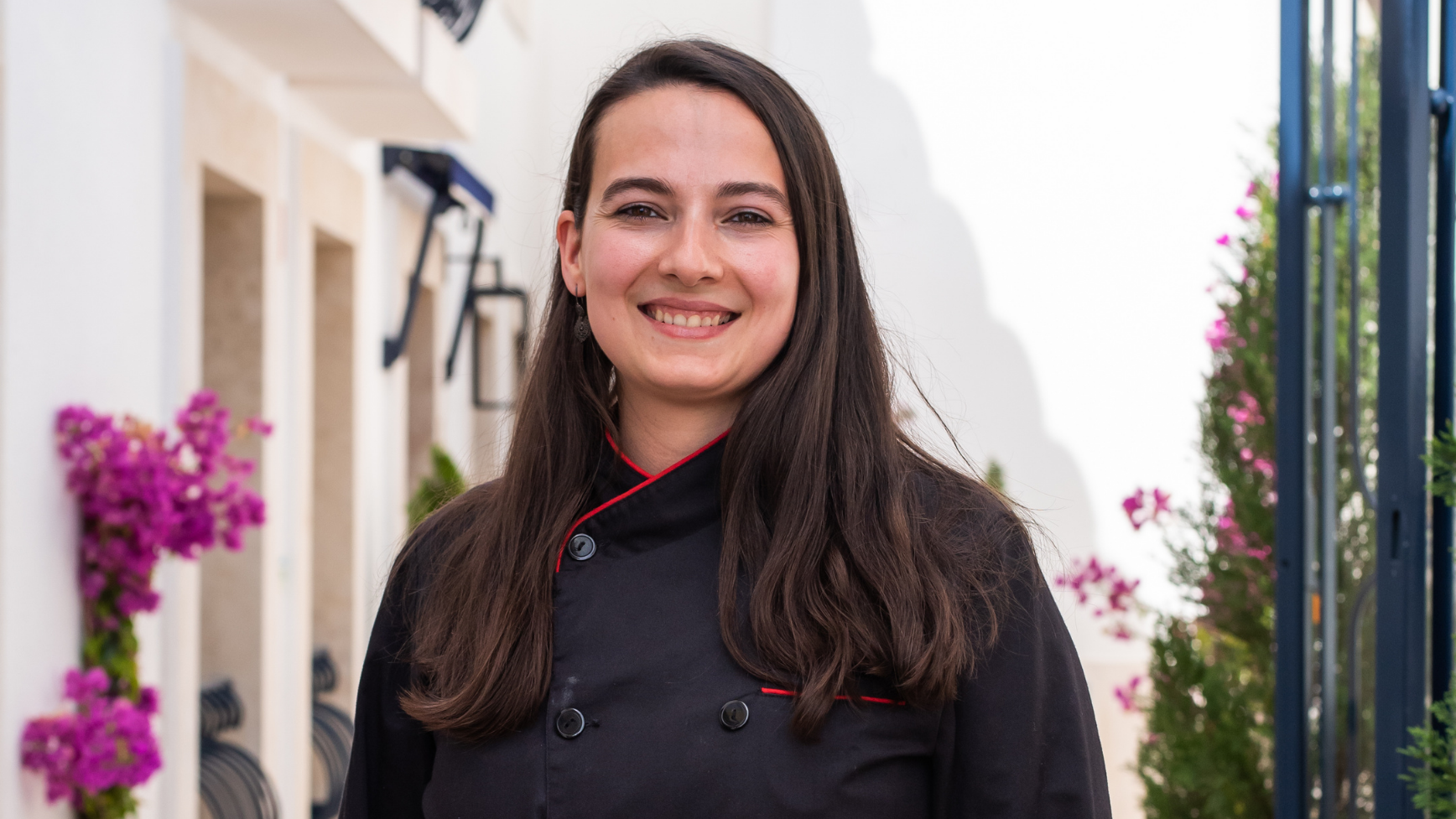 A smiling chef in uniform at Villa Dorothea, a charming Mediterranean property.