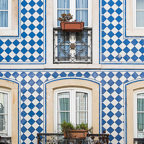 Fachada de hotel con azulejos azules y blancos, ventanas y balcones con plantas Villa Dorothea.