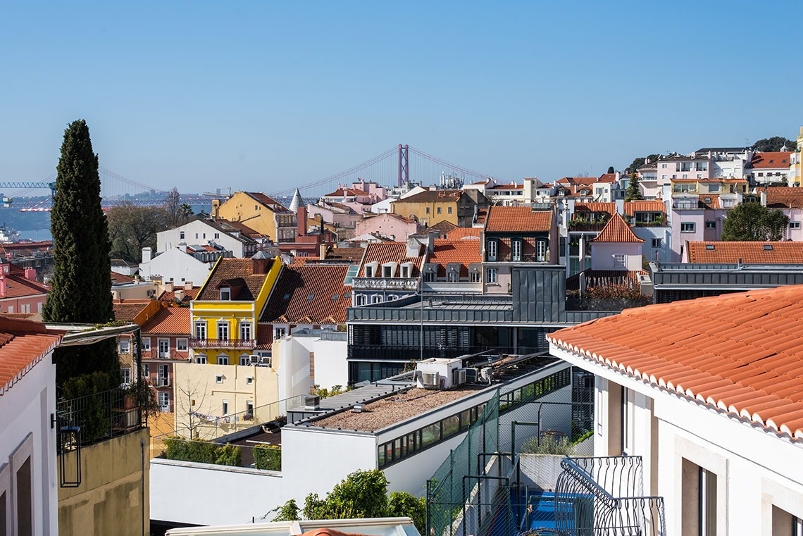 Vista do hotel em Lisboa: telhados vibrantes, edifícios coloridos e Ponte 25 de Abril.