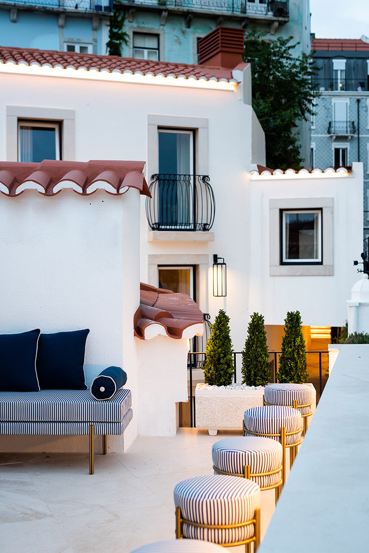 Charming patio seating at Villa Dorothea with striped sofas and ottomans, overlooking historic buildings.