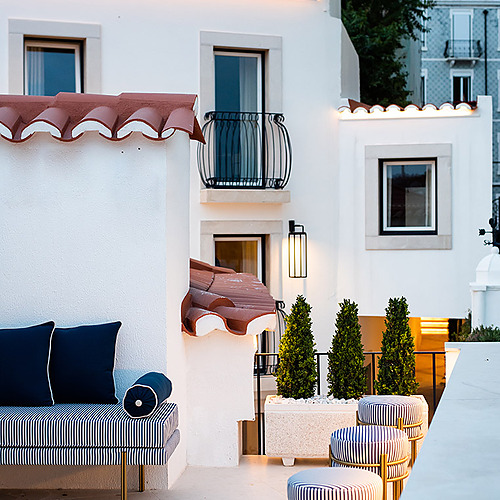 Terraza exterior de hotel con sillones a rayas, otomanas y plantas. Villa Dorothea