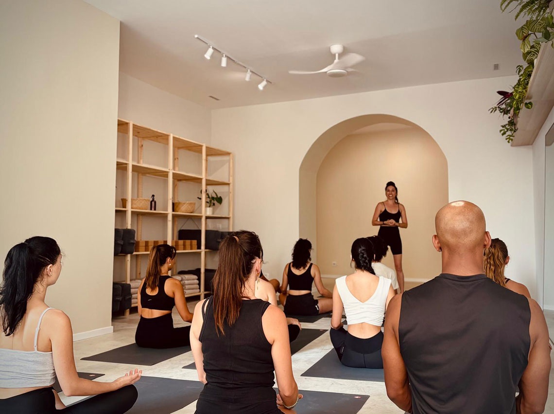 Aula de yoga em Villa Dorothea com instrutor e alunos em meditação.