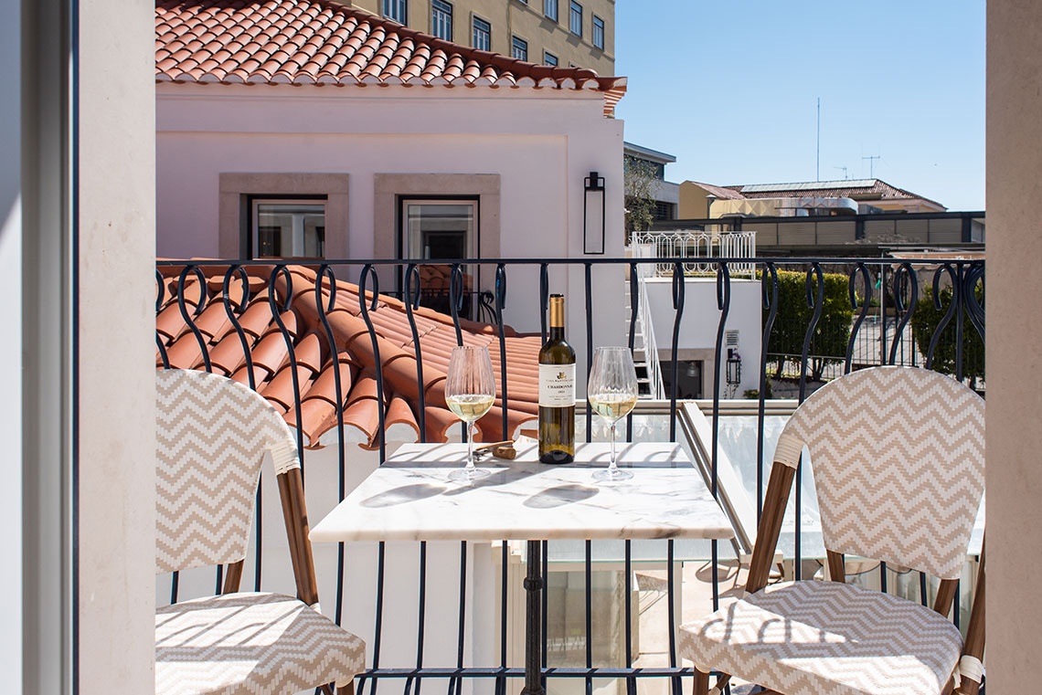 Varanda da Villa Dorothea com duas taças de vinho e mesa, ideal para relaxar.