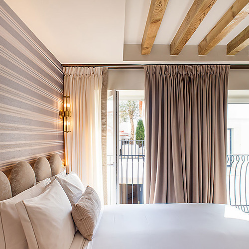 Dormitorio elegante en Villa Dorothea con cabecero tapizado y vistas al balcón.
