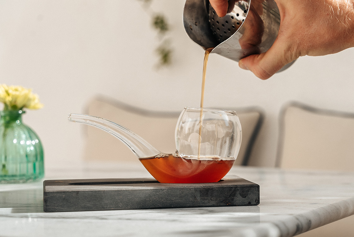 Bartender pouring a cocktail into a unique pipe-shaped glass, ideal for Villa Dorothea guests.