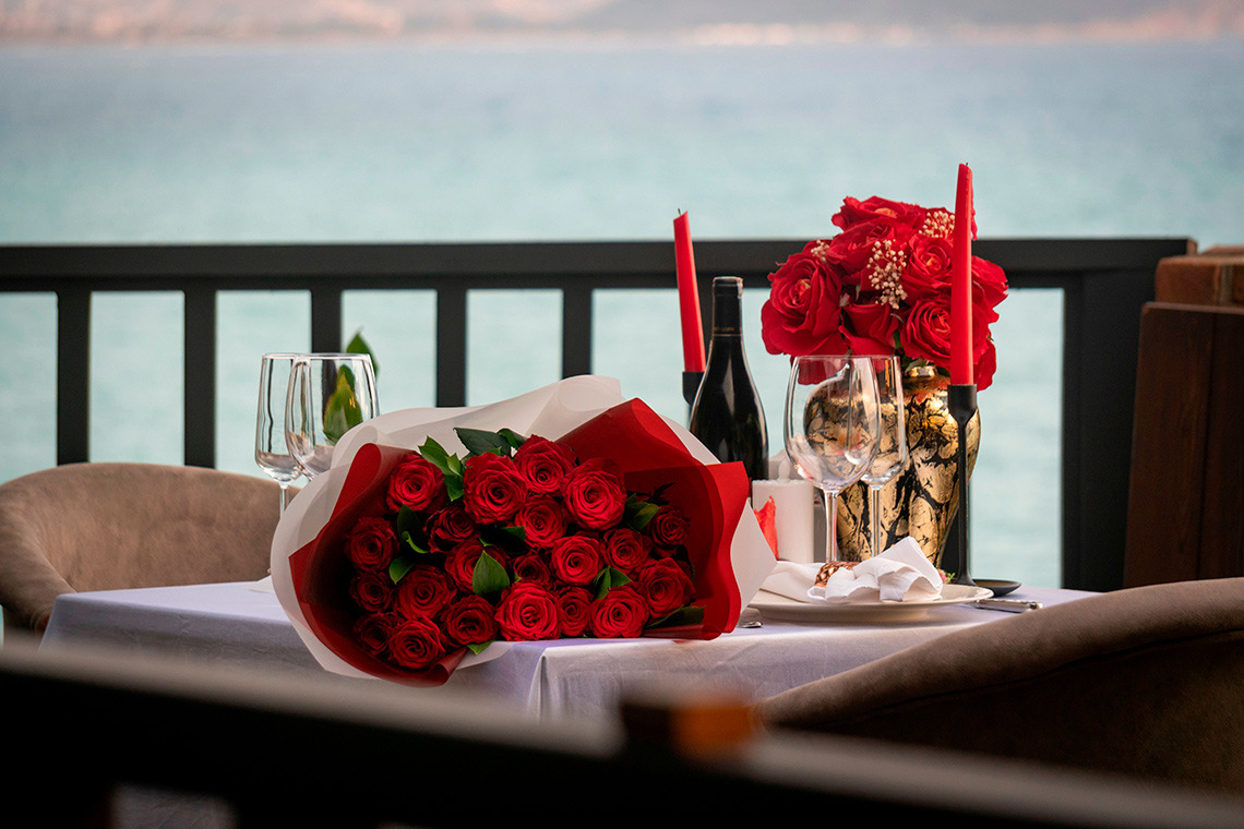 Mesa romântica em hotel com rosas vermelhas, vinho e vista para o mar Villa Dorothea