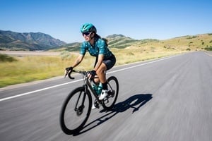 a woman riding a bike down a road with mountains in the background