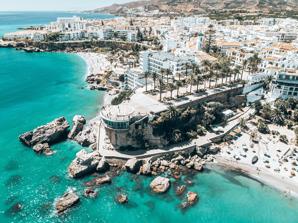 una vista aérea de una playa con edificios blancos y palmeras