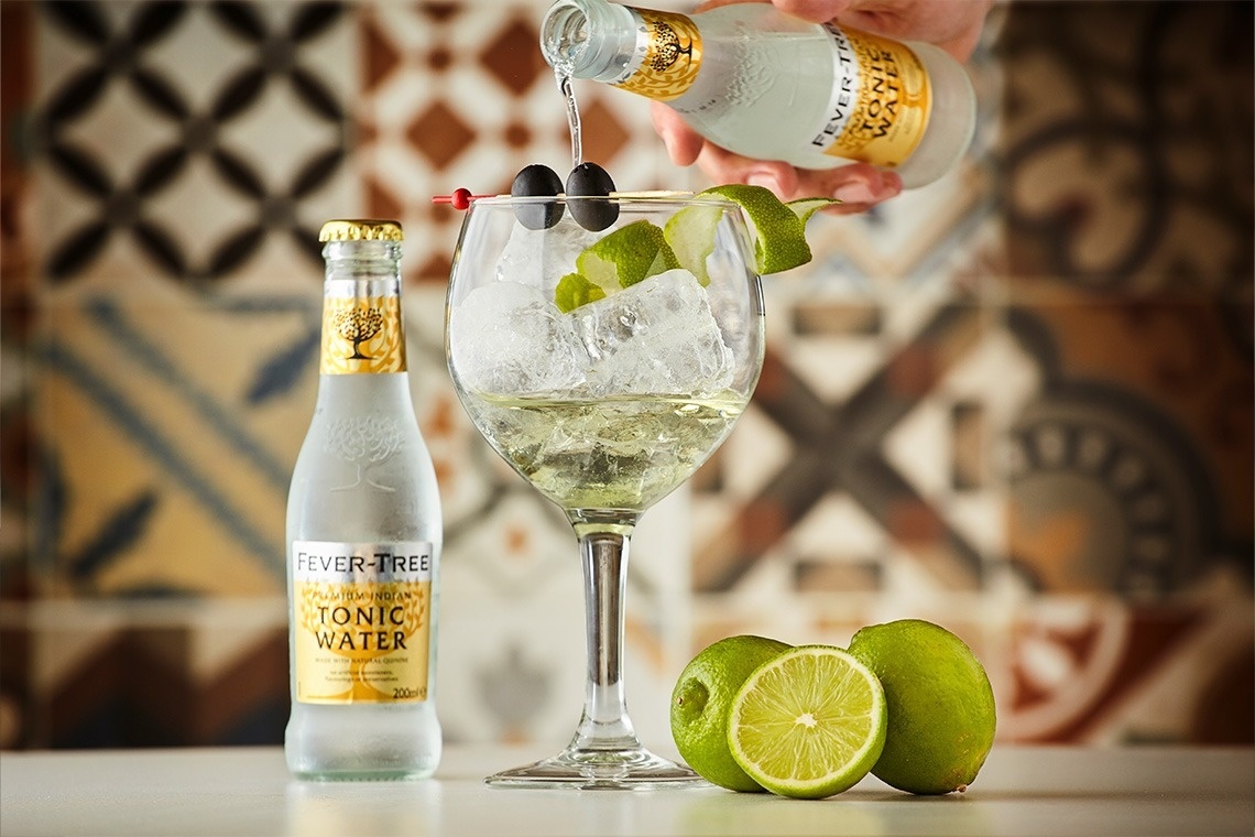 una botella de fever tree tonic water se vierte en un vaso de cóctel