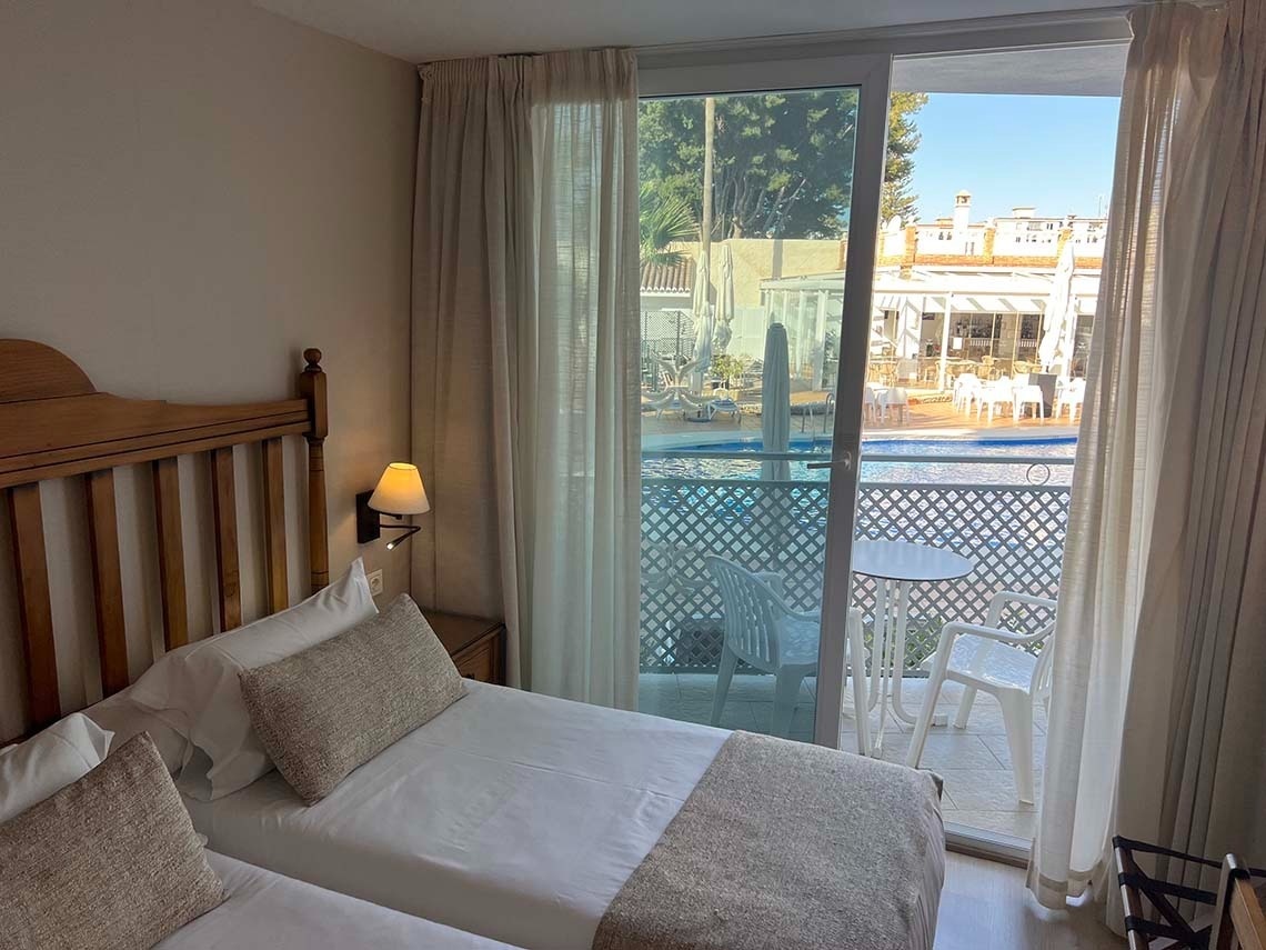 una habitación con dos camas y una ventana que da a una piscina