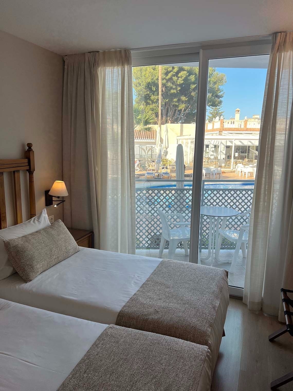 una habitación con dos camas y una ventana con vista a una piscina