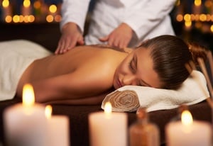 a woman is getting a massage with candles in the background