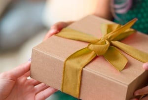 a person is holding a gift box with a yellow ribbon