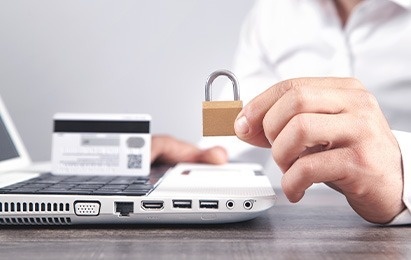 una persona sostiene un candado frente a una computadora portátil .