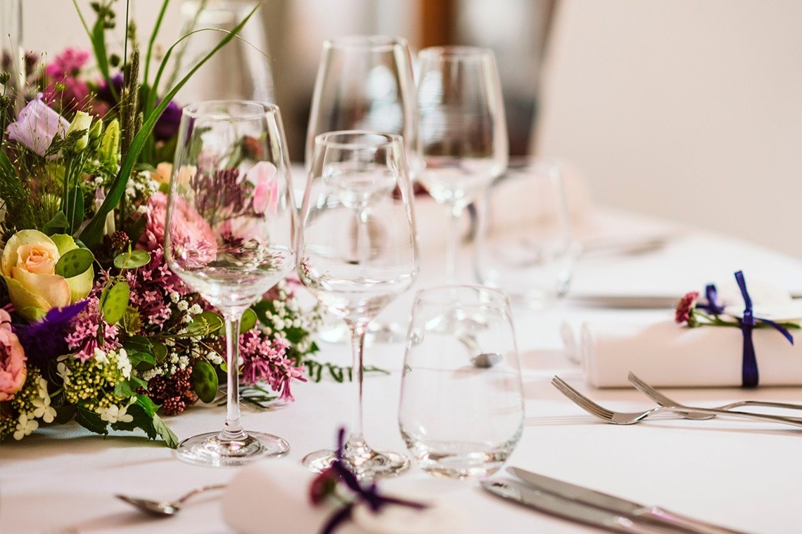 una mesa con copas de vino y flores en el centro