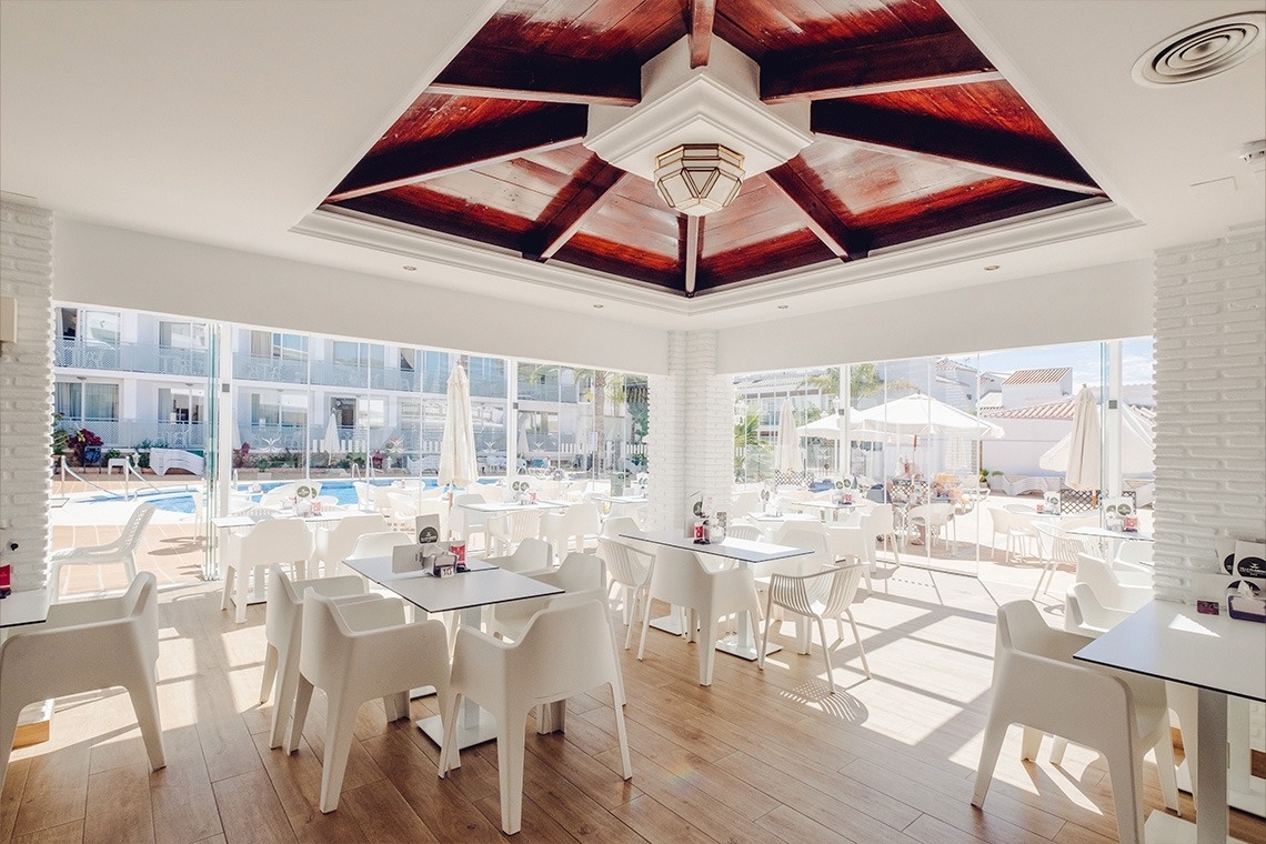 un restaurante con mesas y sillas blancas y un techo de madera