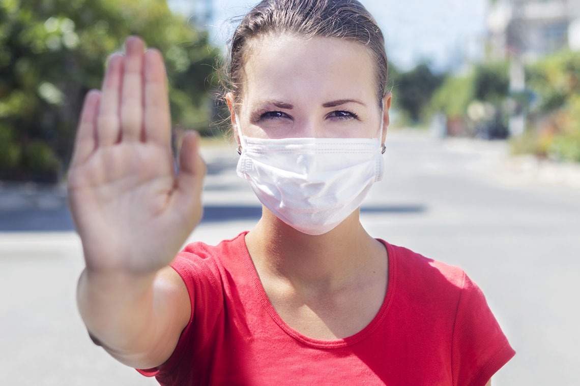 una mujer con una máscara facial hace una señal de stop