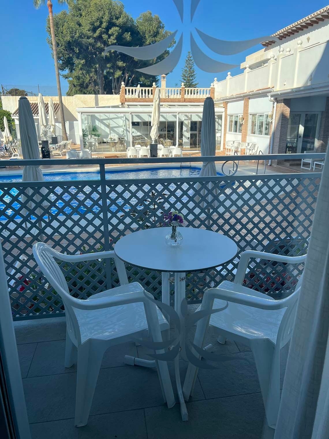 una mesa y sillas frente a una piscina en un hotel