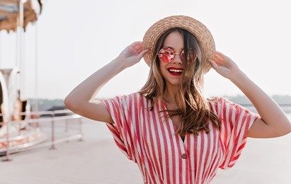 una mujer con un sombrero de paja y gafas de sol está sonriendo .