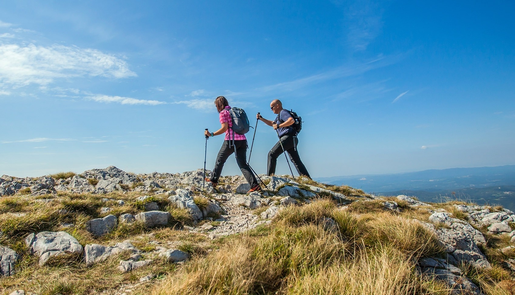 a man and a woman hiking on top of a mountain