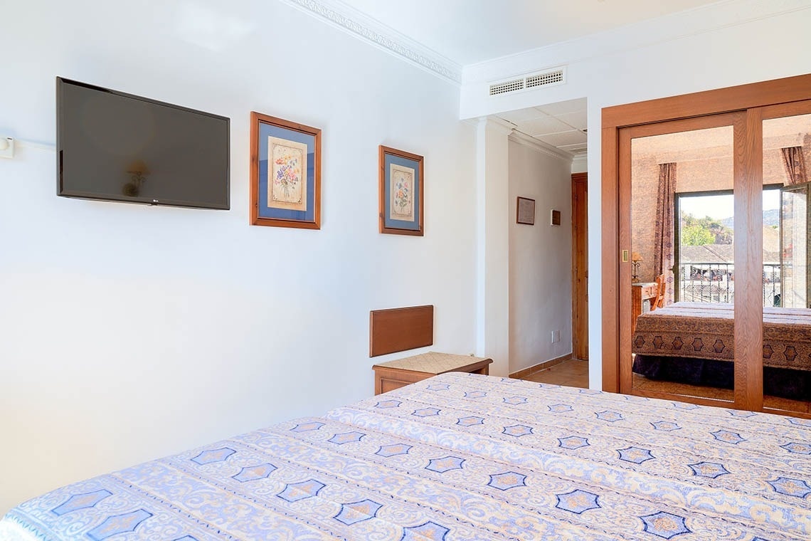 un dormitorio con una cama y una televisión en la pared