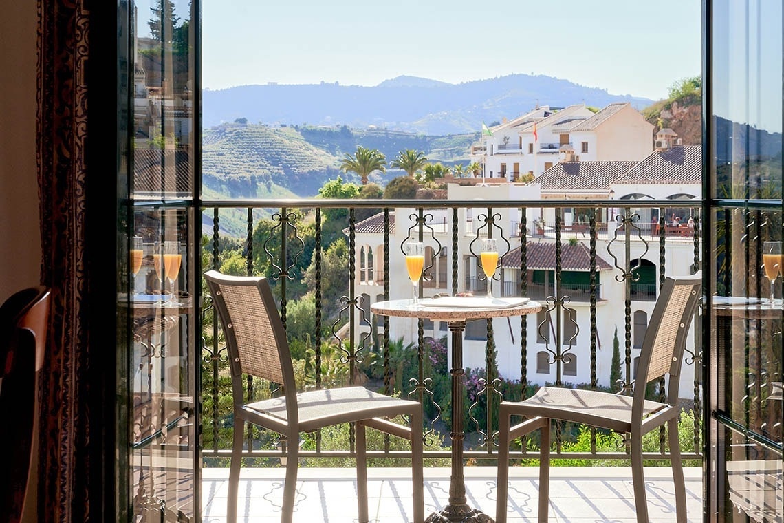 una mesa y dos sillas en un balcón con una vista de las montañas