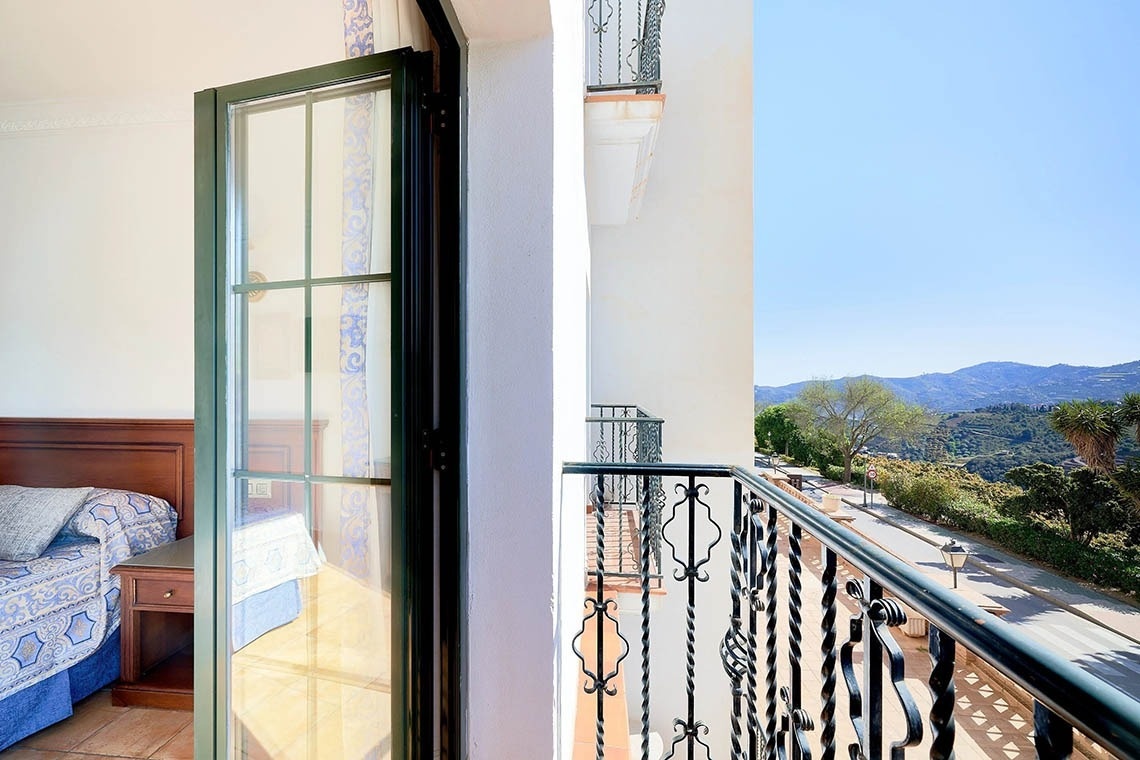 una habitación con una cama y un balcón con vistas a las montañas