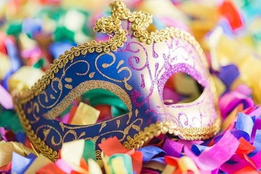 a carnival mask is sitting on top of a pile of confetti .
