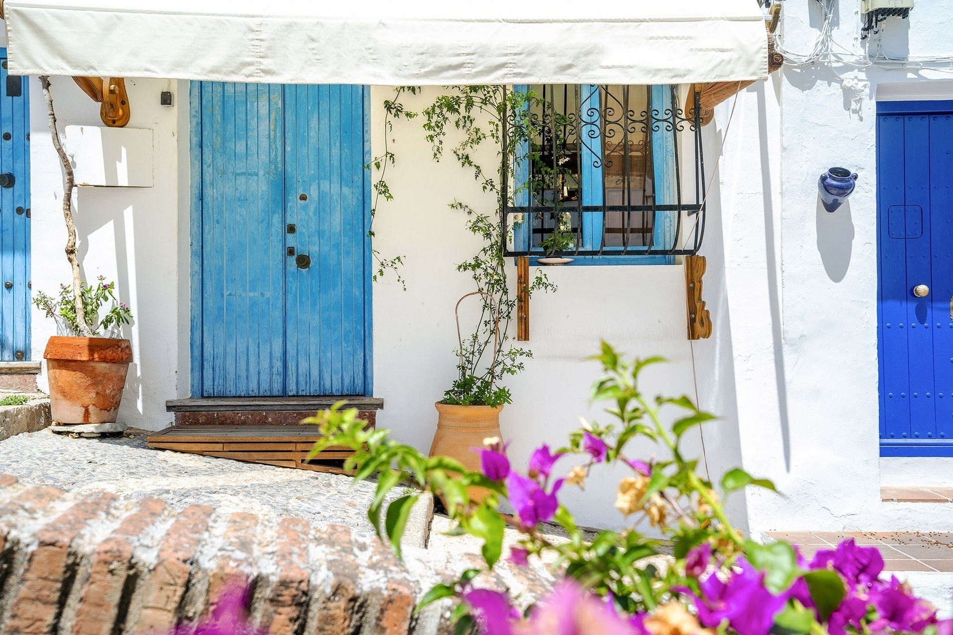 un edificio blanco con puertas azules y una ventana