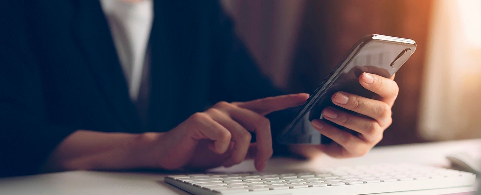 una persona sostiene un teléfono inteligente frente a un teclado