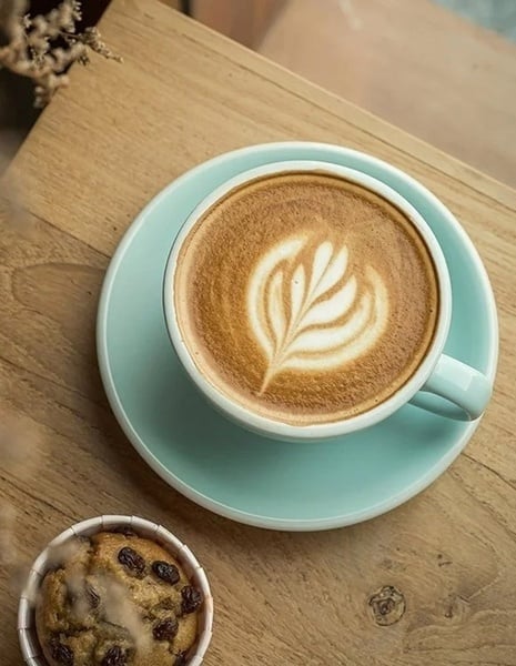 una taza de café y un muffin en una mesa de madera