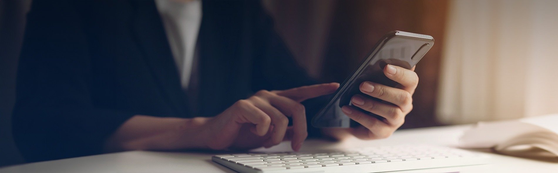 una persona está usando un teléfono inteligente junto a un teclado