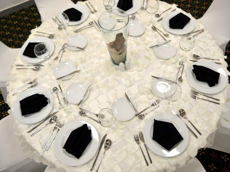 una mesa redonda con platos blancos y servilletas negras