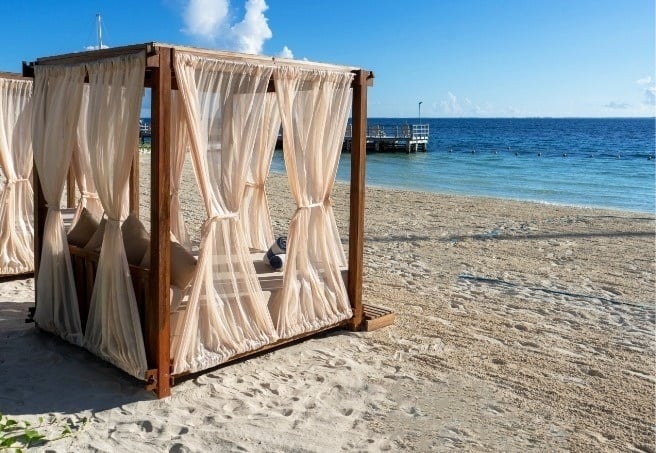 a canopy bed sits on a sandy beach near the ocean