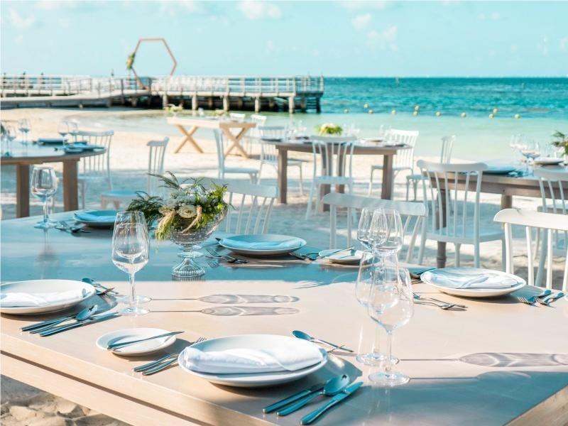 una mesa en la playa con platos y copas de vino