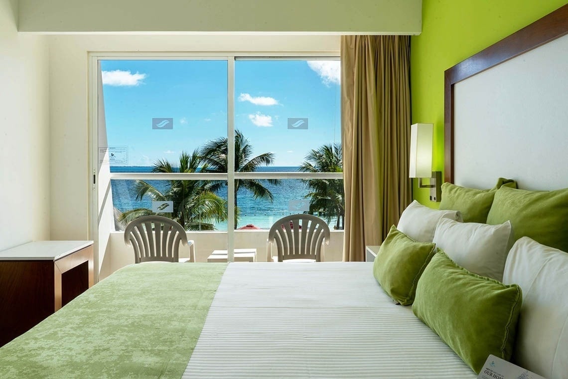 una habitación con una cama y dos sillas con vista al océano