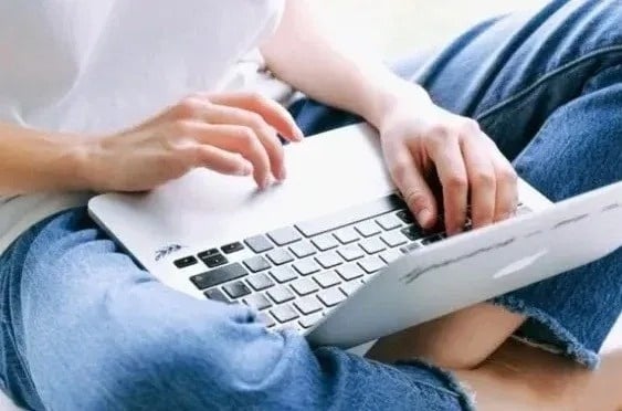 una persona está sentada en el suelo usando una computadora portátil .