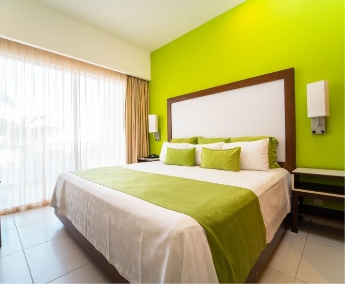 una habitación de hotel con una cama y una pared verde
