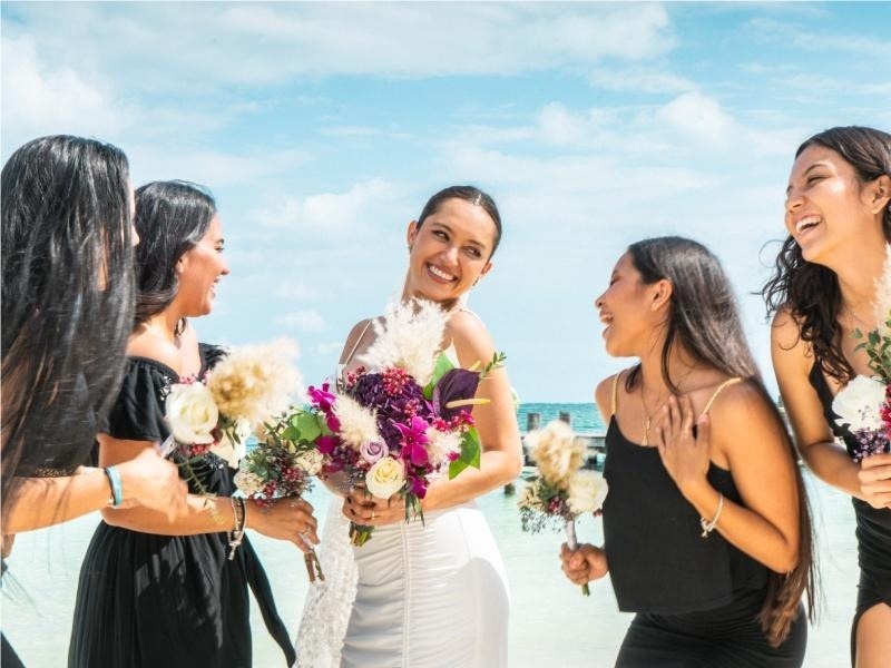 una novia y sus damas de honor se ríen mientras sostienen ramos de flores