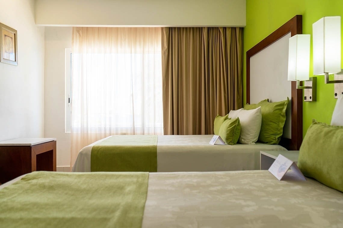 a hotel room with two beds and a green wall