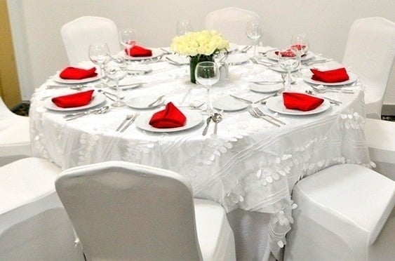 a round table with white plates and red napkins