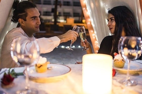 a man and a woman are toasting with champagne at a dinner table .
