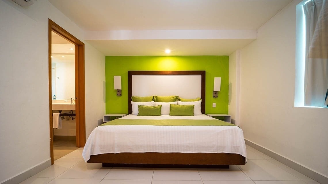 a hotel room with a bed and a green wall