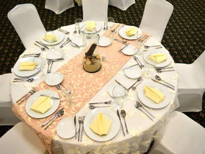 una mesa redonda con platos y cubiertos y un jarrón en el medio