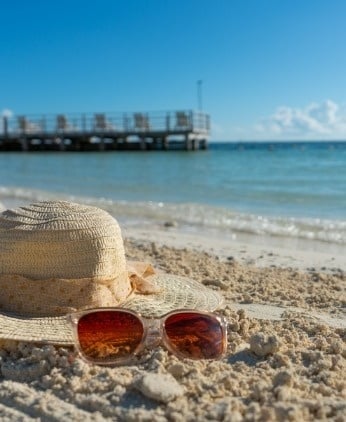 un sombrero de paja y gafas de sol están en la playa .