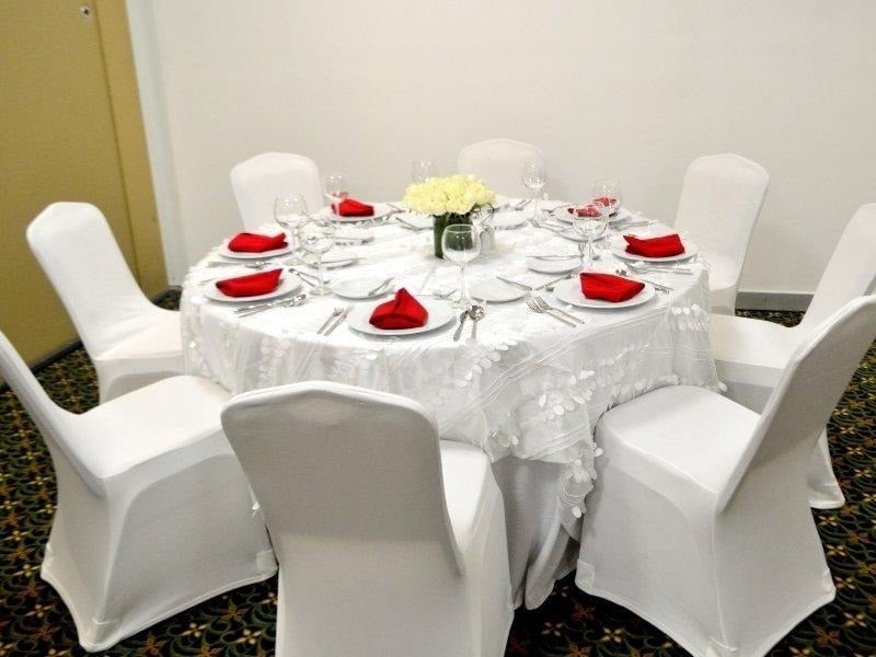 a round table with white chairs and red napkins