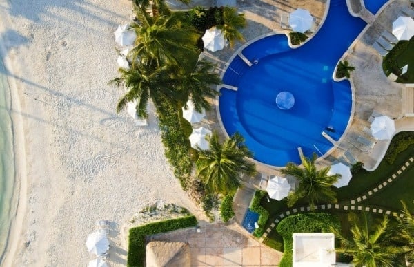 una vista aérea de una piscina rodeada de palmeras y sombrillas