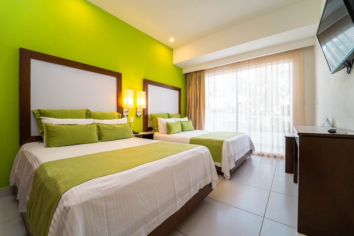 a hotel room with two beds and green walls